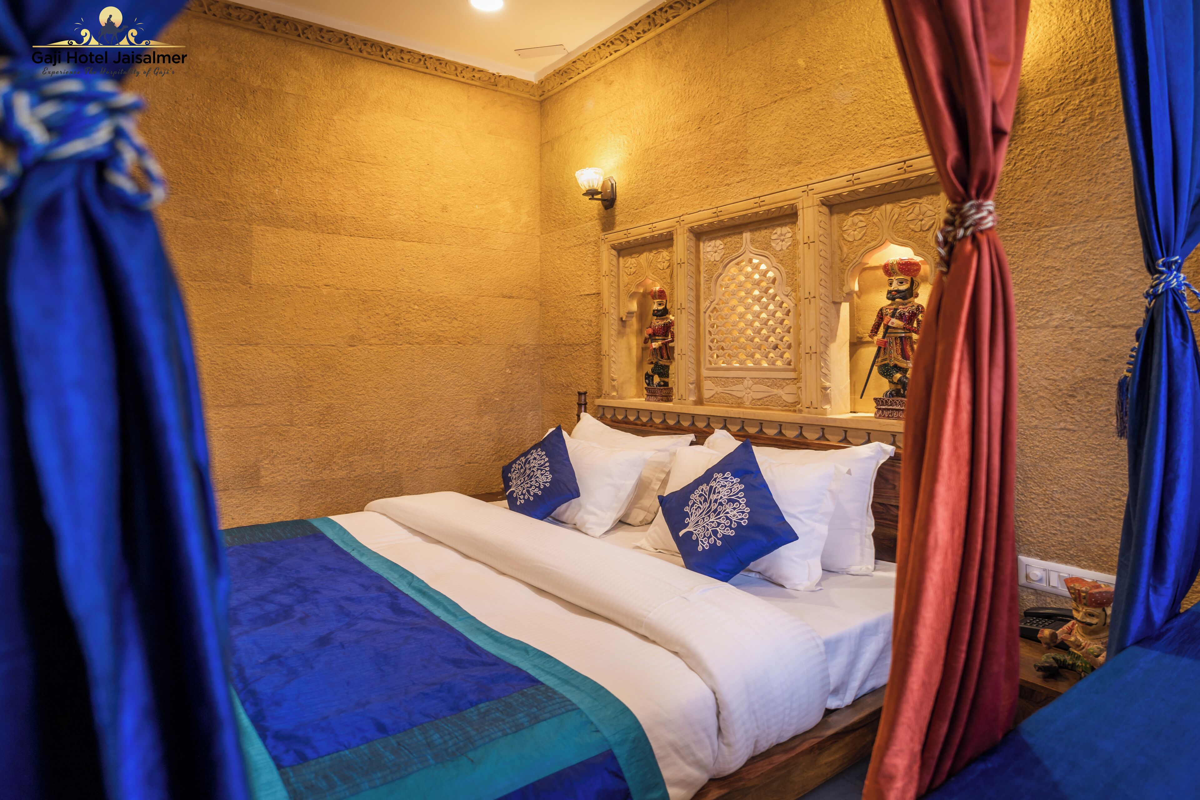 A room with a bed, blue and white bedding, a decorative mirror, and a wall with a textured pattern.