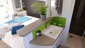 Un dormitorio pequeño con cama, mesita de noche y una ventana.