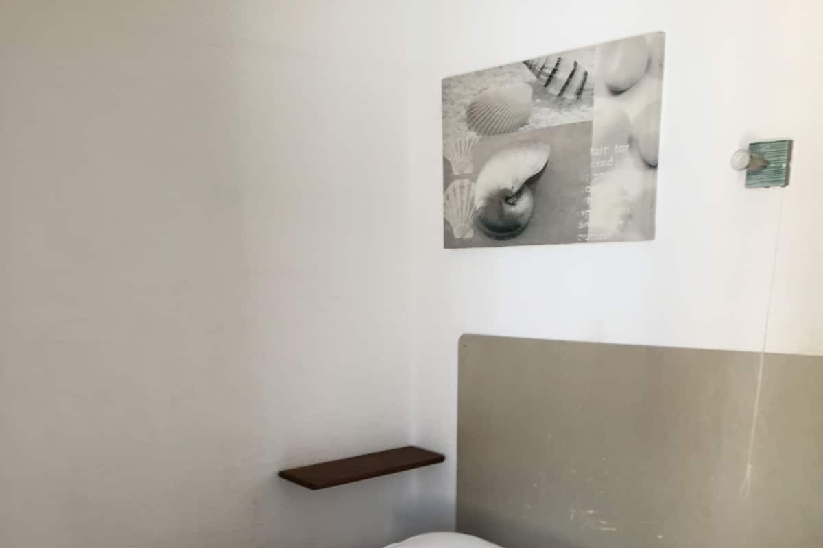 Una cama bien hecha con sábanas blancas y una toalla enrollada con detalles decorativos.