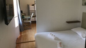 A hotel room with a bed, a desk, a chair, and a small shelf. - Hôtel Restaurant Le 8 (Mandelieu-La-Napoule)
