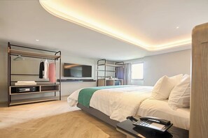 A modern hotel room with a bed, a bedside table with a phone, a TV, a wardrobe, and a mirror. - Patumwan House (Bangkok)