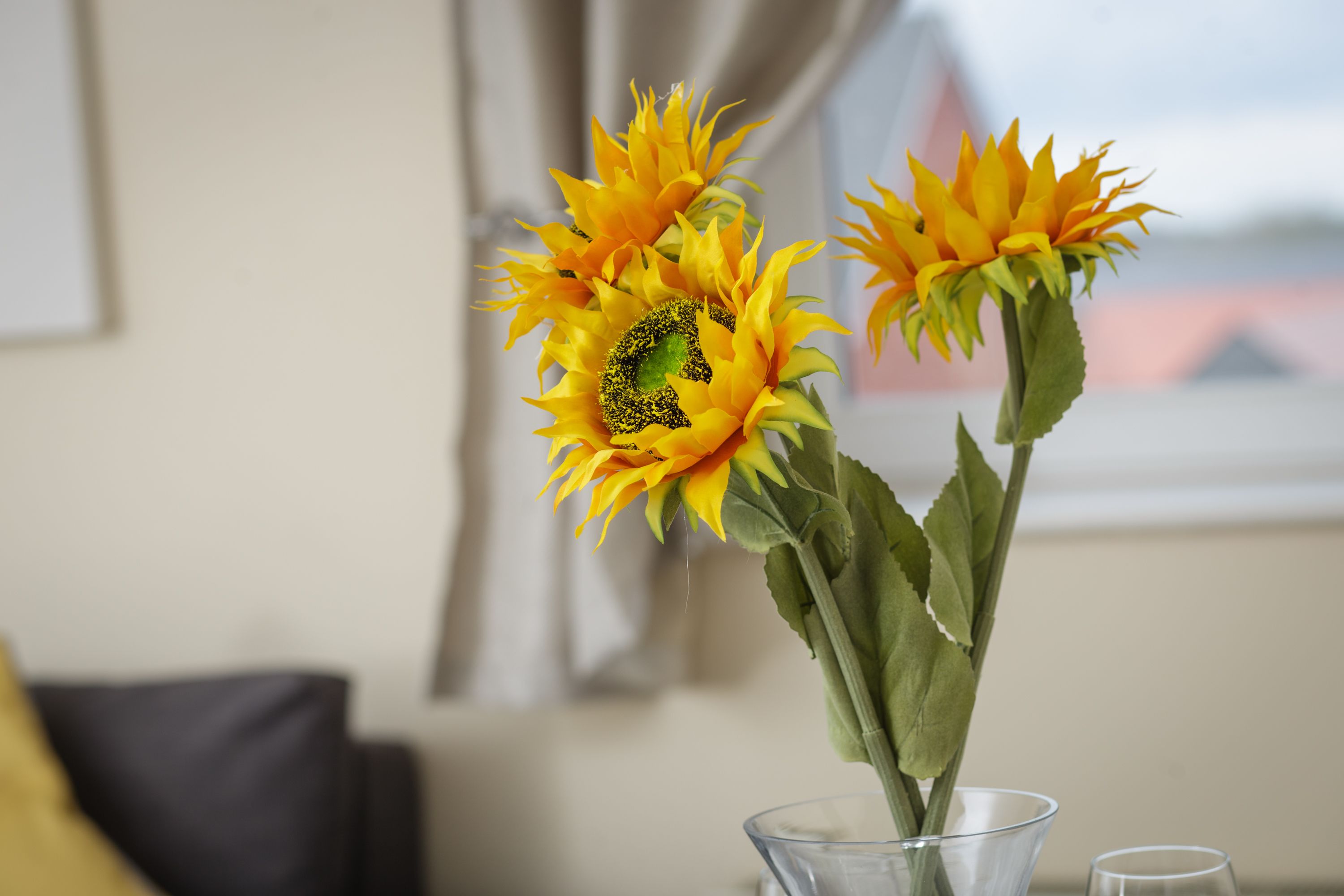 Un florero de vidrio transparente con dos girasoles sobre una mesa.