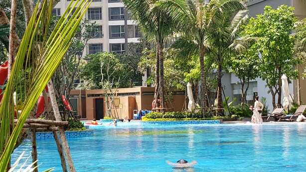Ein Swimmingpool mit klarem, blauem Wasser, umgeben von Palmen und Liegestühlen.