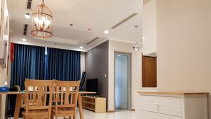 Ein modernes Wohnzimmer mit einem Holzesstisch, zwei Stühlen, einem weißen Schrank und einem Fernseher.