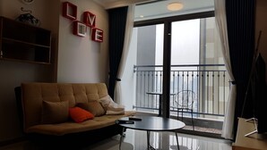 Ein modernes Wohnzimmer mit einer Couch, einem Couchtisch und Blick auf eine Stadtlandschaft durch große Fenster.