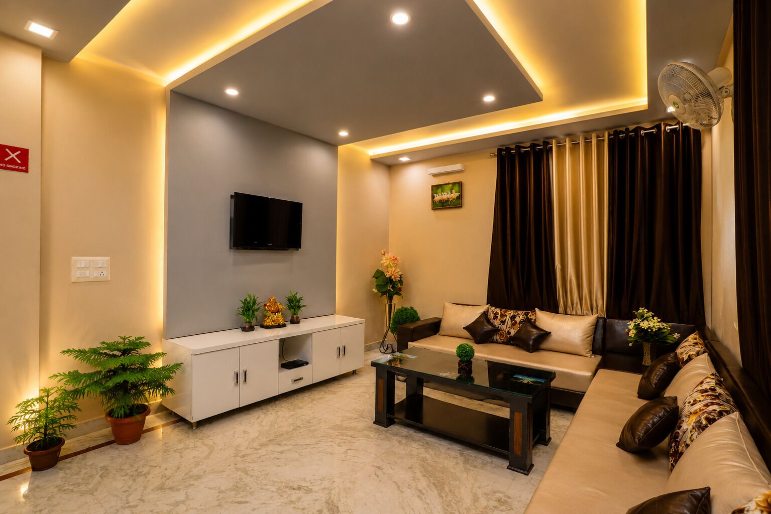 Una sala de estar moderna con televisor de pantalla plana, sofá, mesa de centro y plantas en macetas.