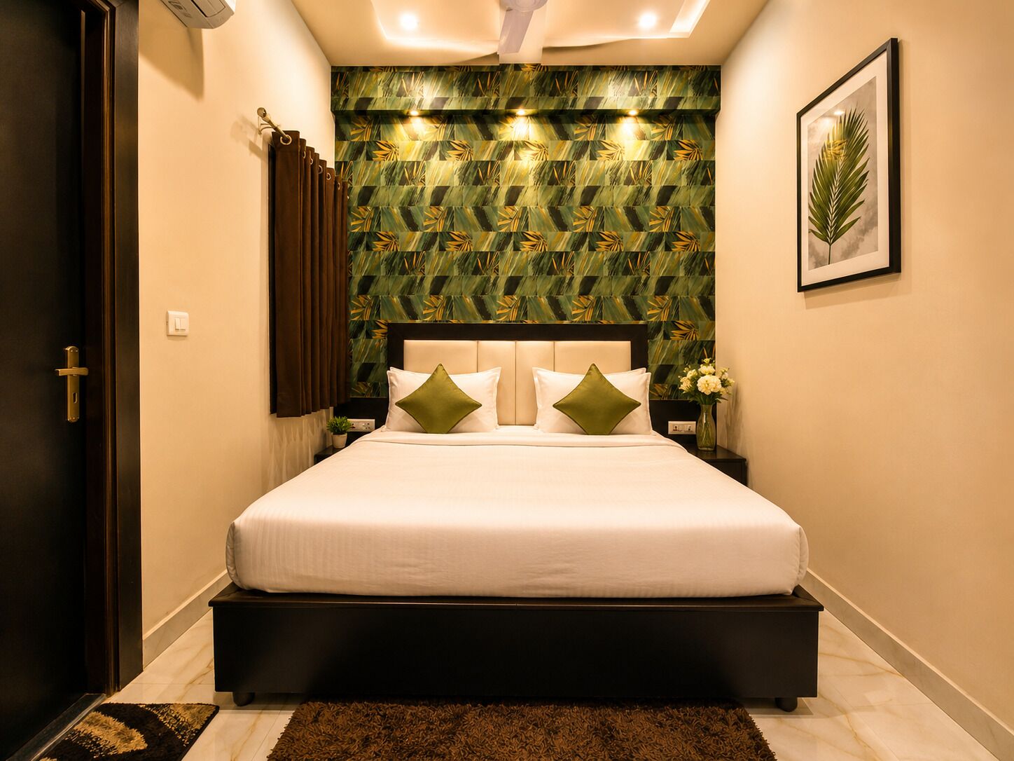 A hotel room with a bed, a headboard, a nightstand, a wall-mounted air conditioner, a framed picture, and a door.