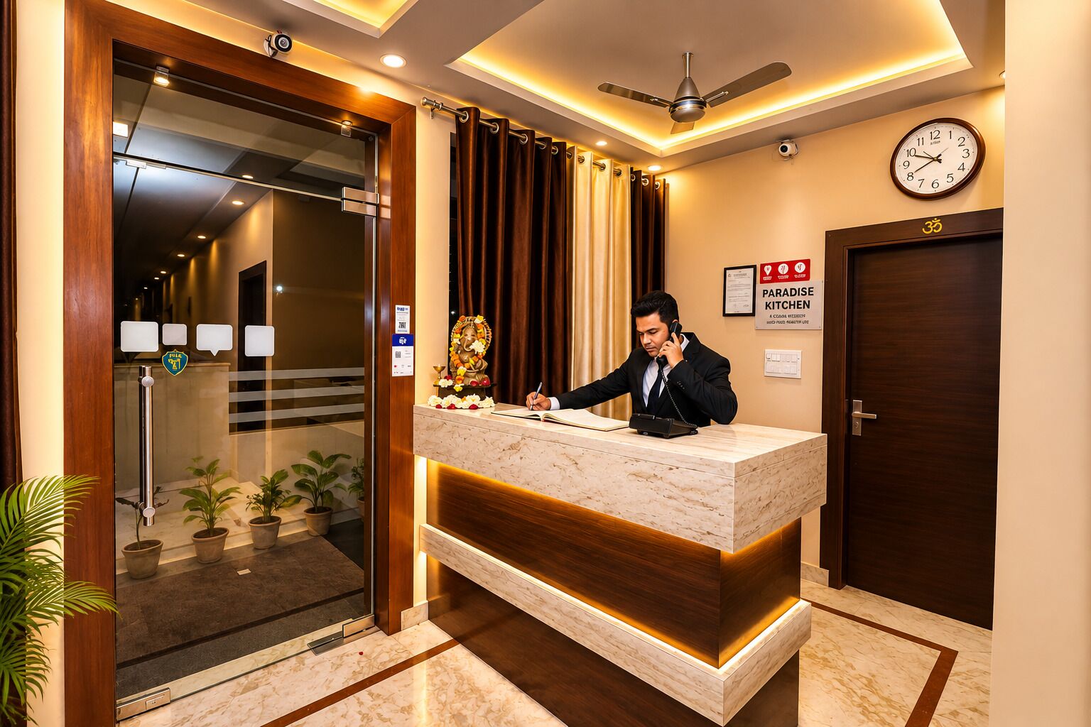 En hotelreception med receptionist, et ur og skilt til Paradise Kitchen.