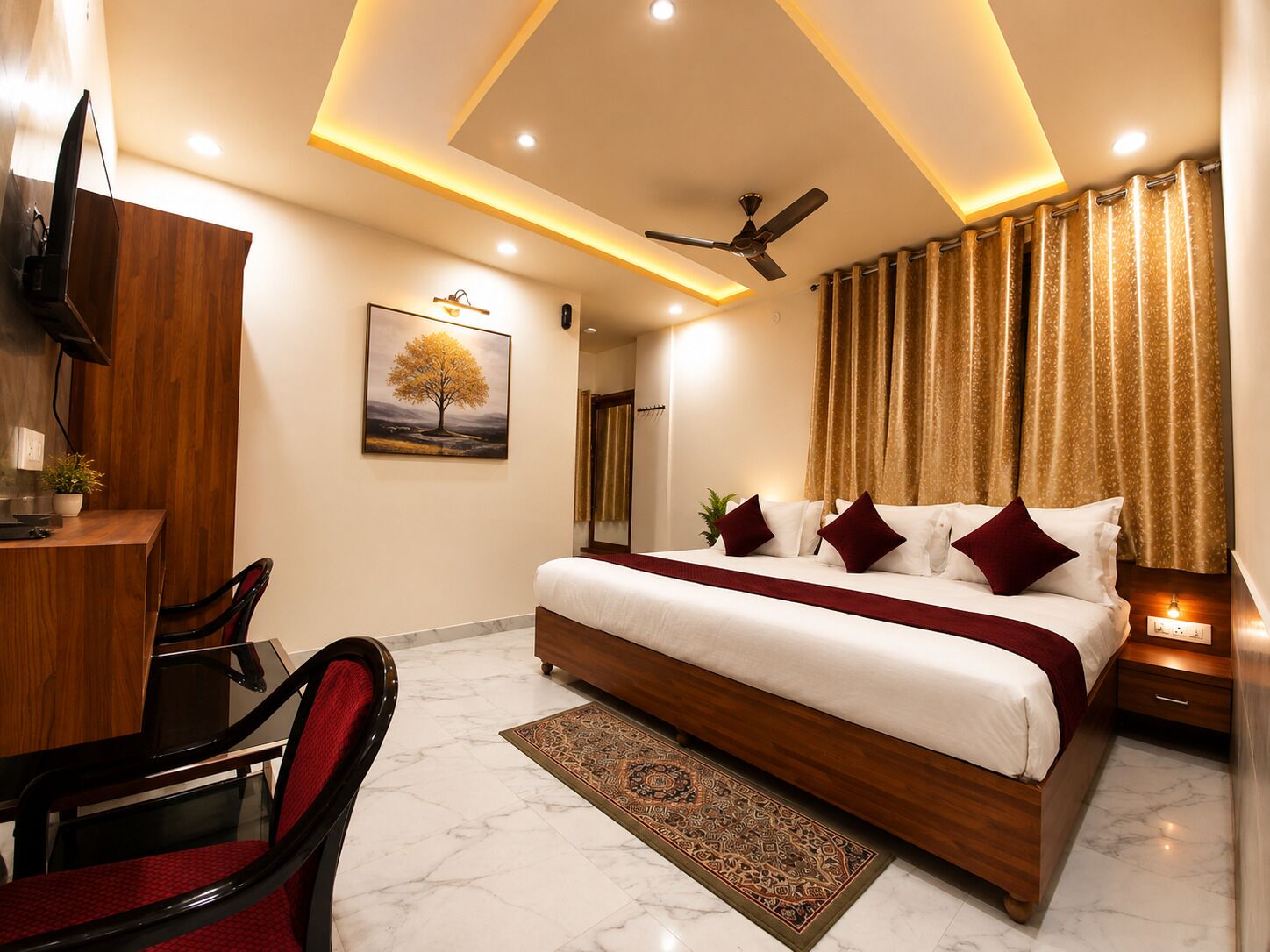 A hotel room with a large bed, a desk, a chair, a ceiling fan, and a painting on the wall.
