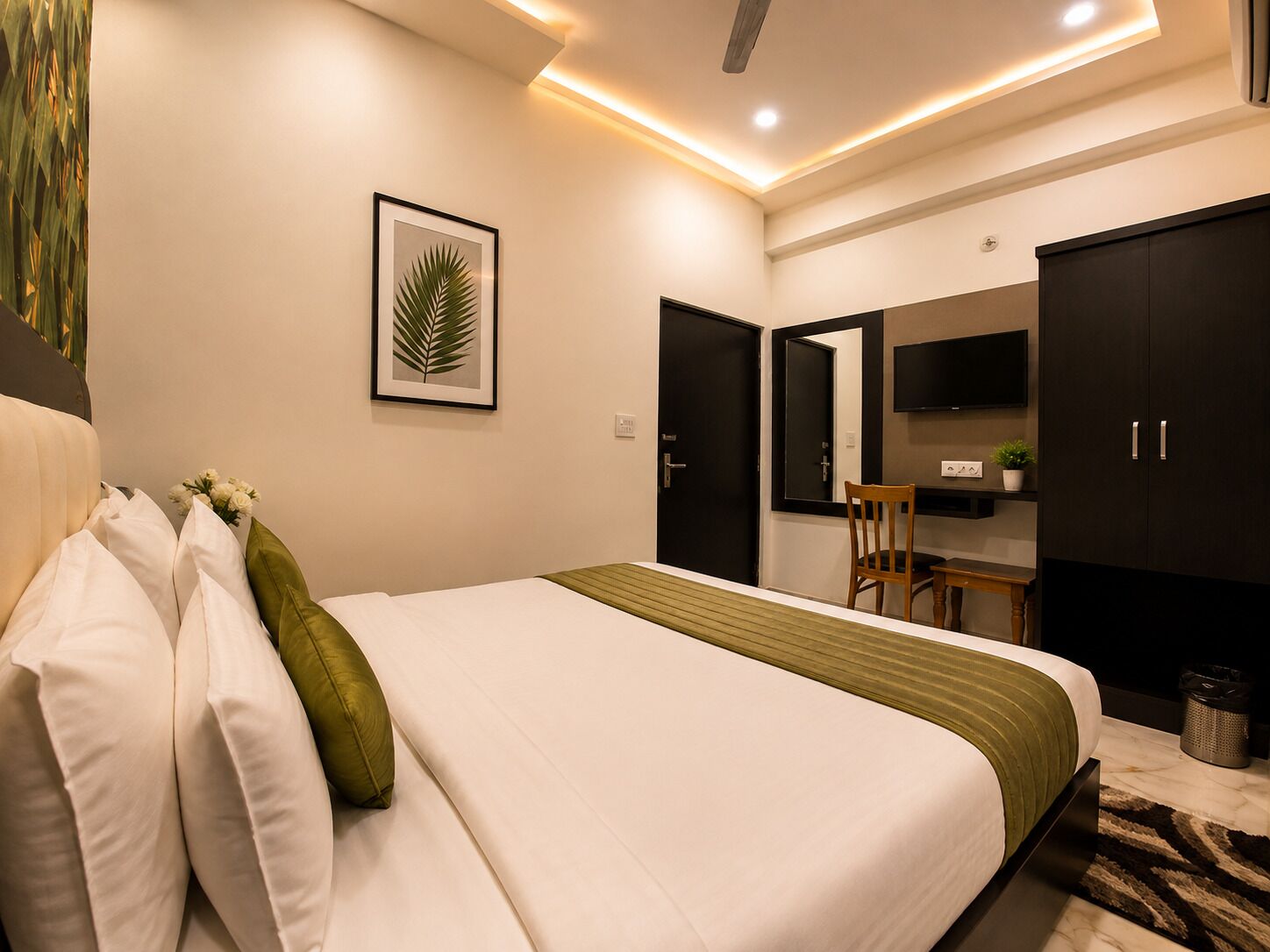 A hotel room with a bed, a desk, a chair, a television, and a wardrobe.