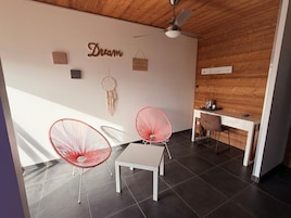 Una habitación moderna con techo de madera, un escritorio blanco, dos sillas rojas y un ventilador de techo.