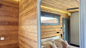 A bedroom with wooden paneling, a large ornate mirror, a bed with pillows, and a door in the background. - Bio Motel (Saint-Vulbas)