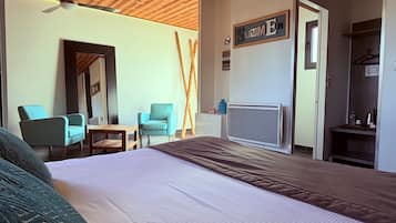 A hotel room with a large bed, two chairs, a desk, a mirror, a ceiling fan, and a sign that reads "Summer".