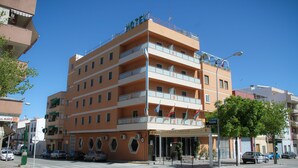 Ett hotell med flera våningar och balkonger, en skylt som visar att det är en restaurang, och en klarblå himmel i bakgrunden.