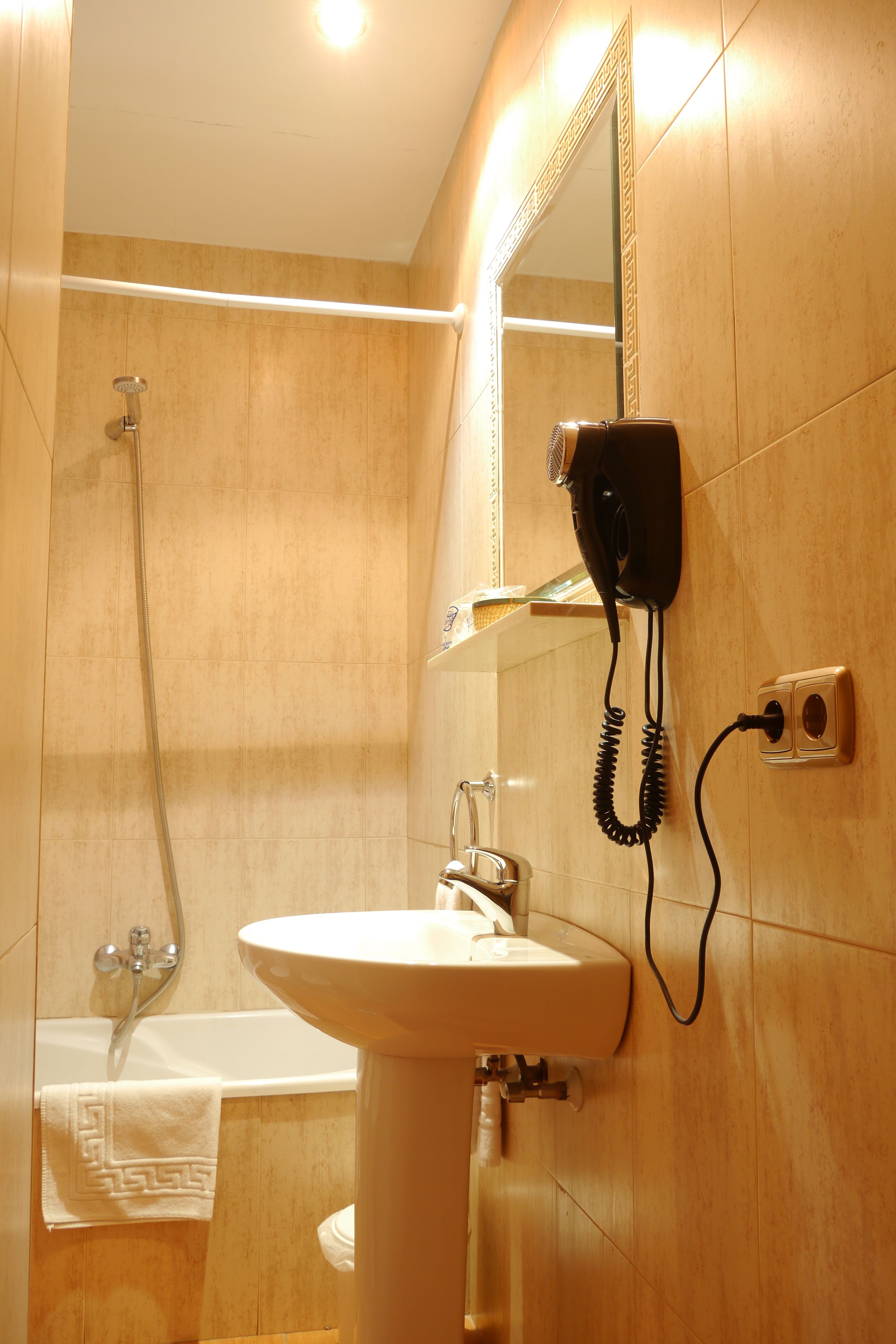 Un baño con lavamanos, espejo, secador de pelo y ducha.