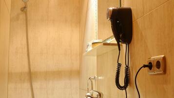 Un baño con lavamanos, espejo, secador de pelo y ducha.