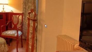 A room with a wooden chair, a table, a lamp, and a radiator.
