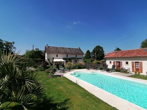 A swimming pool with lounge chairs, a grassy area, and two buildings with red-tiled roofs. - La Vieille Gorce (Asnois)