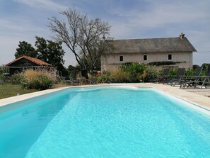 A swimming pool with lounge chairs and a building in the background. - La Vieille Gorce (Asnois)