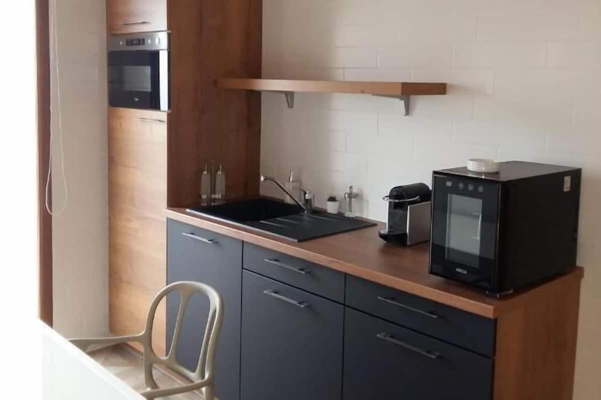 A compact kitchen with a built-in oven, a microwave, and a coffee maker on the counter.