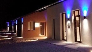 A building with multiple doors, some illuminated by lights. - What Else Hotel (Saint-Vulbas)