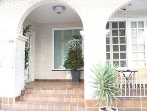 A building with a tiled entrance, a potted plant, and a sign with text. - Hotel Llansola (Sant Carles de la Rapita)