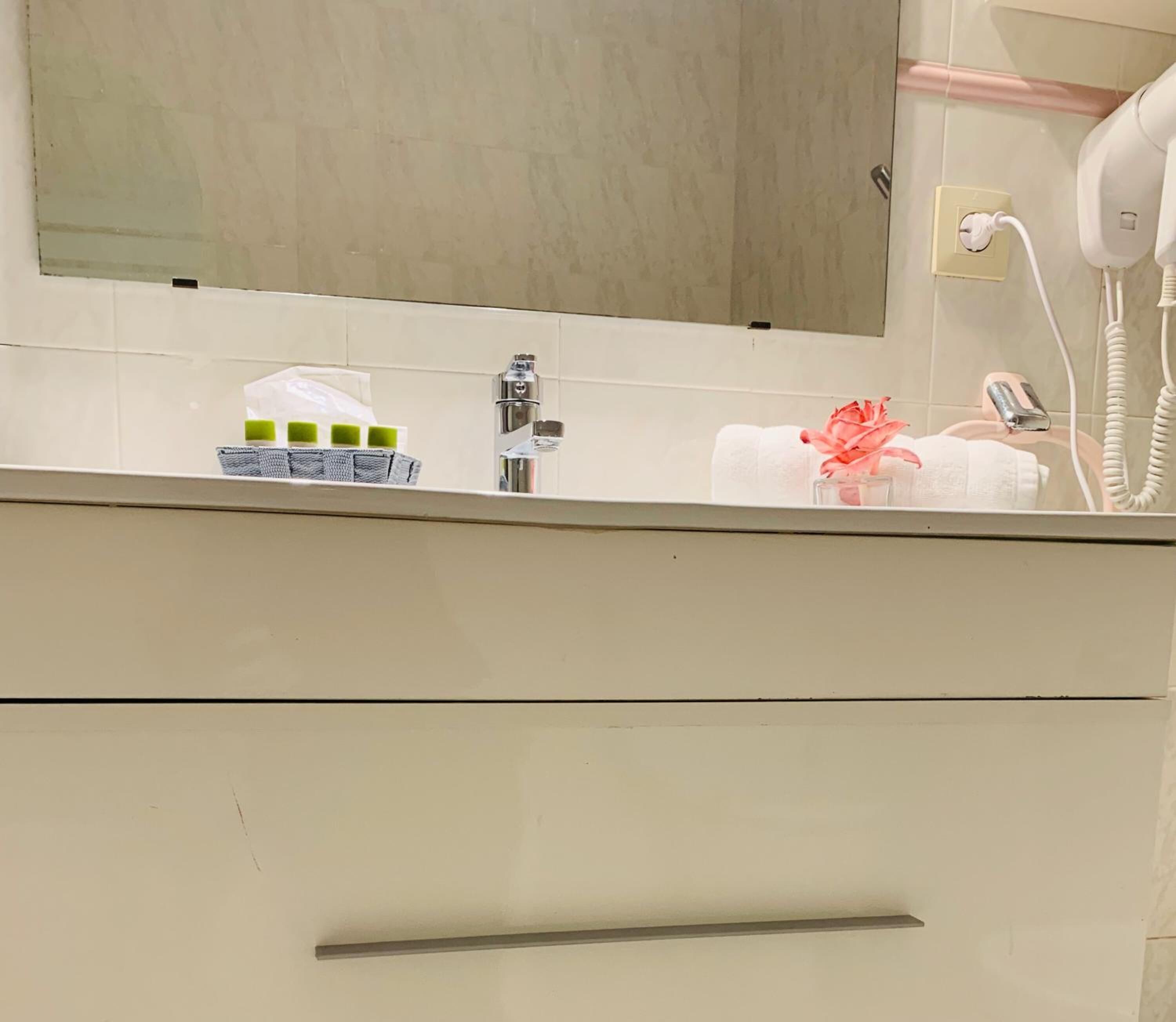 A bathroom vanity with a mirror, a towel, a bottle, and a small container.