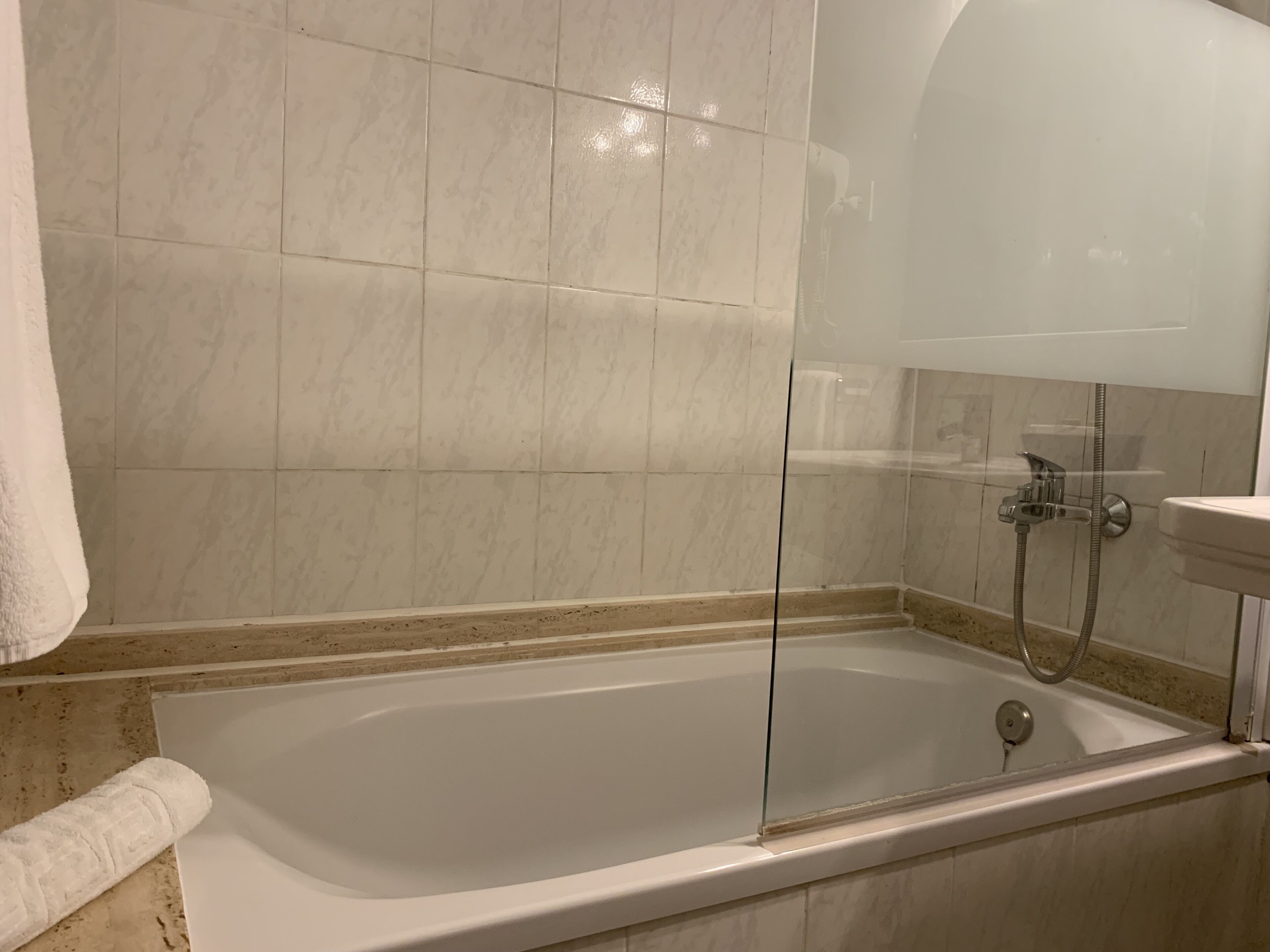 Un baño moderno con ducha envuelta en vidrio, una bañera y un lavamanos blanco.