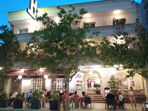 An outdoor cafe area with tables and chairs, surrounded by potted plants. - Hotel Llansola (Sant Carles de la Rapita)