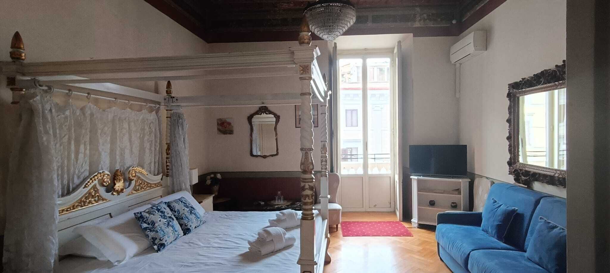 Un dormitorio con cama con dosel, televisor y sofá azul.
