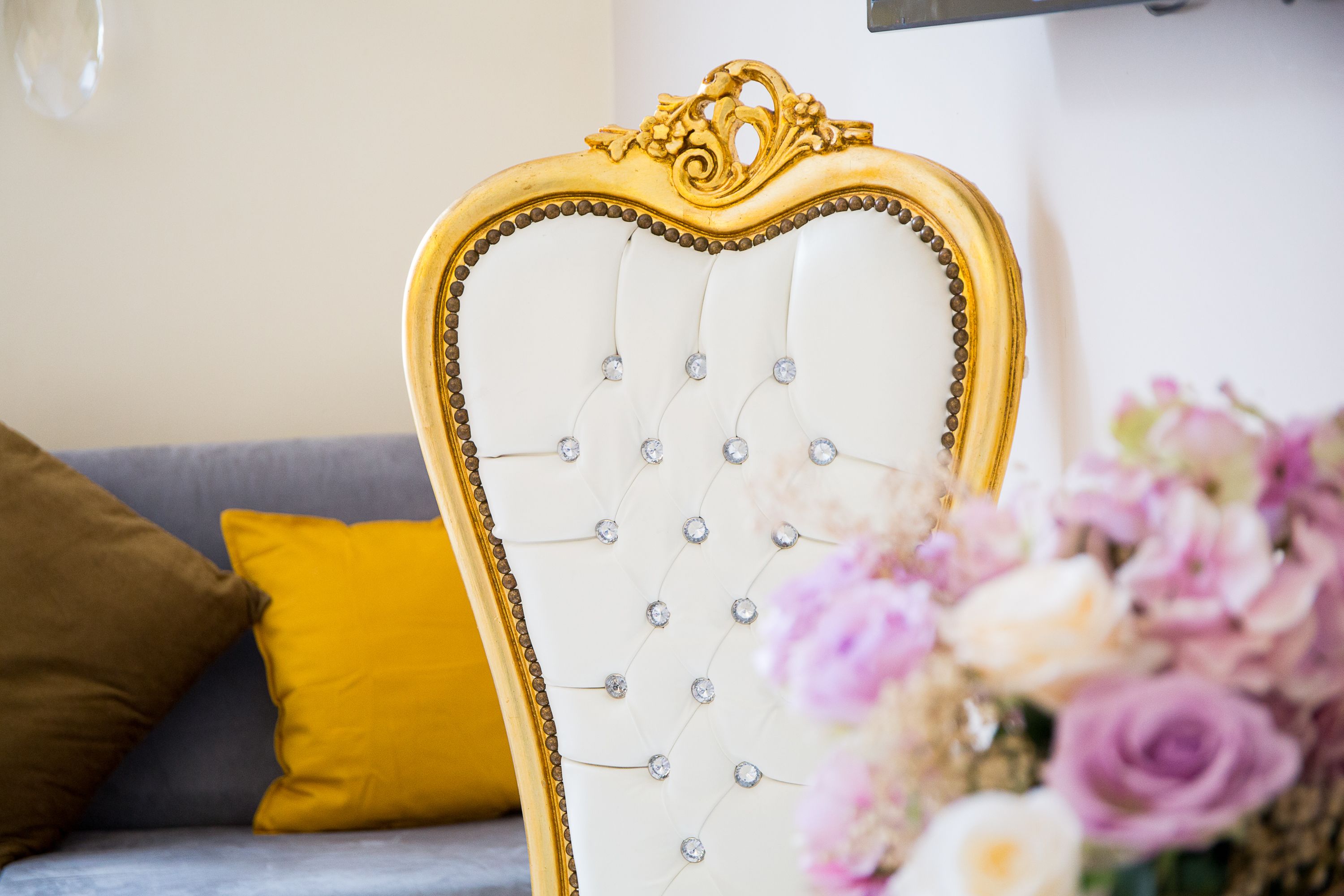 Ein luxuriöser Raum mit einem herzförmigen, gepolsterten Kopfteil, einer Couch mit Kissen und einer Blumenkomposition.