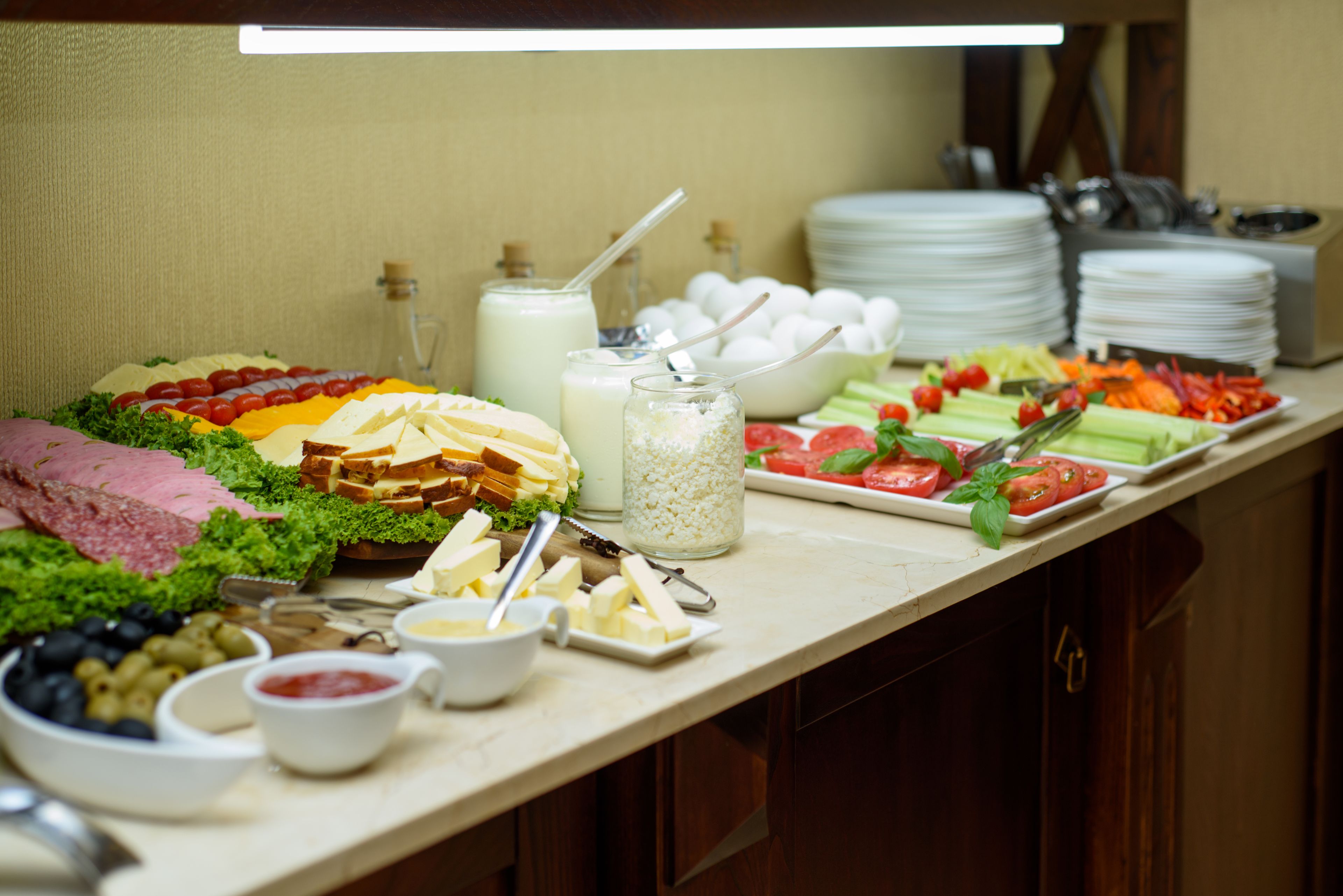 A buffet table with various food items including cheese, meats, and vegetables.