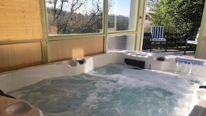 Un jacuzzi con vistas a un jardín y una silla afuera.