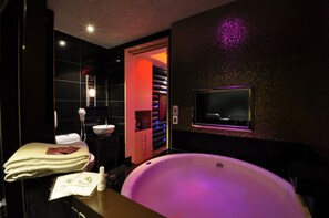 A modern bathroom with a large bathtub, a vanity with a sink, and a mirror. - Jinspa Resort Hotel (New Taipei City)