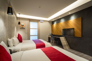 A hotel room with two beds, a desk, a chair, a TV, and a window. - Jinspa Resort Hotel (New Taipei City)