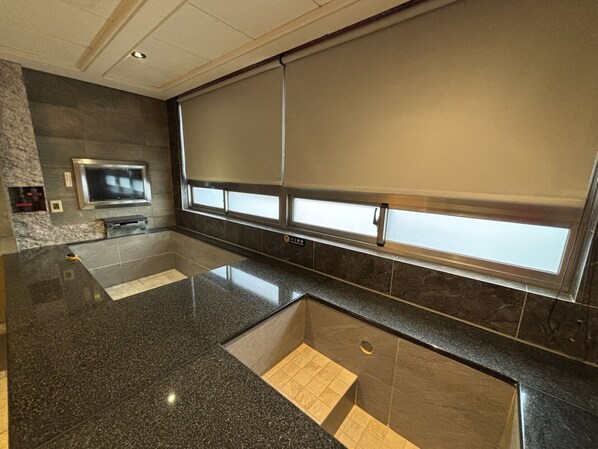 Una cocina moderna con encimeras de granito, horno empotrado y un amplio ventanal con persianas.
