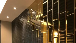 A modern hotel lobby with a black and gold wall design, a reception desk, and a television displaying a news channel. - Jinspa Resort Hotel (New Taipei City)