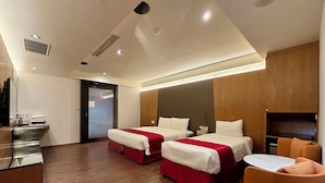 A hotel room with two beds, a desk, a chair, and a TV. - Jinspa Resort Hotel (New Taipei City)
