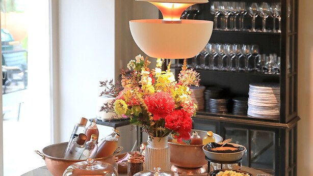 A round table with a variety of food items, a decorative lamp, and a glass cabinet in the background. - Auberge Basque (Saint-Pee-sur-Nivelle)
