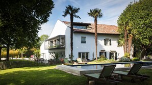 A modern house with a swimming pool, two palm trees, and a grassy lawn. - Auberge Basque (Saint-Pee-sur-Nivelle)
