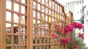 A wooden lattice fence with various plants and flowers.