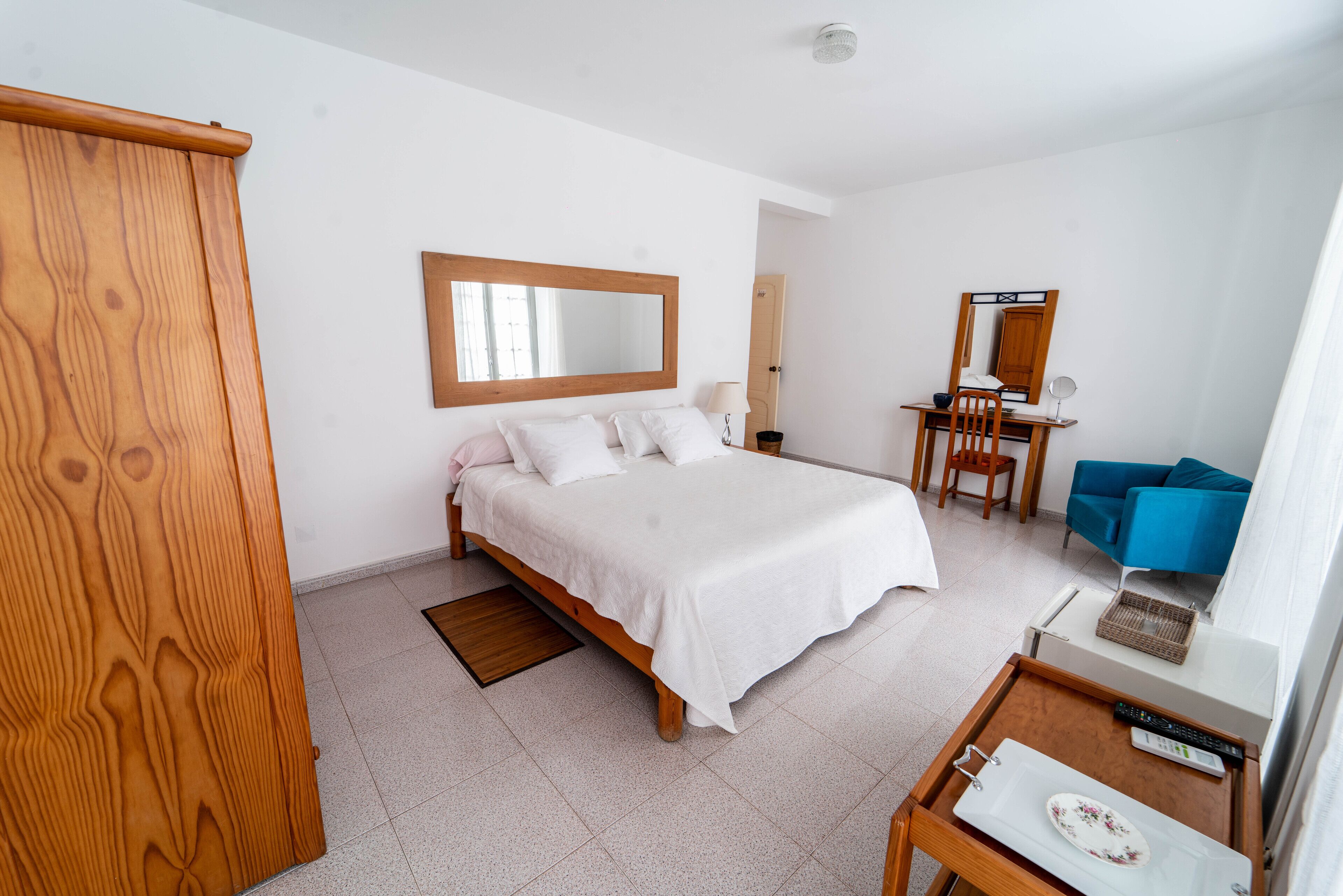 Ein Schlafzimmer mit Bett, Schreibtisch, Stuhl, Kleiderschrank und Spiegel.