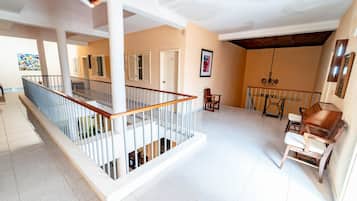 Un interior amplio con una escalera, un comedor con un piano y vistas al exterior.