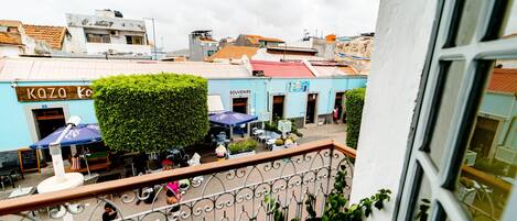 Pátio com mesas ao ar livre, uma loja de lembranças e um edifício azul com uma placa.