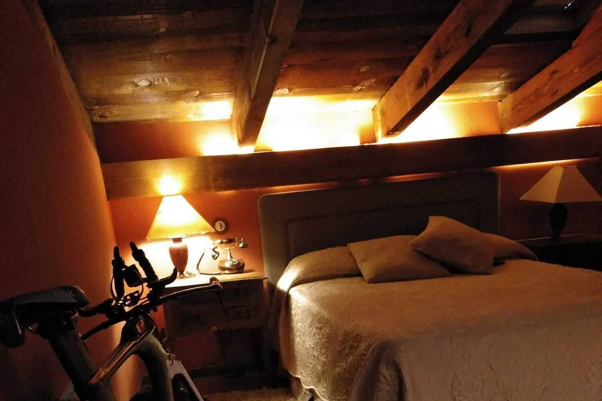 Un dormitorio acogedor con una cama, una mesita de noche, una lámpara y una bicicleta.