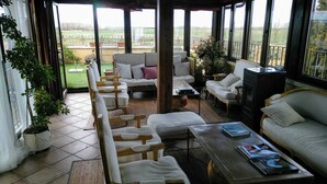 Un espace extérieur aménagé, abrité et doté d’un canapé, de chaises et d’un téléviseur.