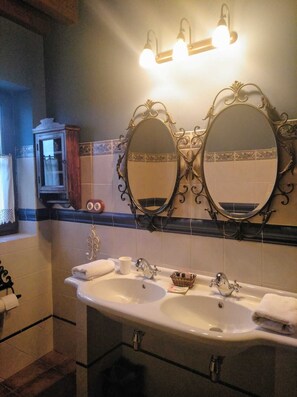 Een badkamer met twee grote spiegels, een wastafel en een kast met handdoekhouder.