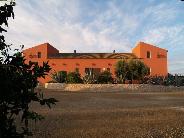 A building with a flat roof, rectangular shape, and a stone wall in front.
