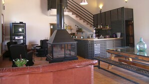 A cozy living room with a fireplace, a television, and a bar area with shelves. - Casa Rurales Ventaseca (Mazarron)