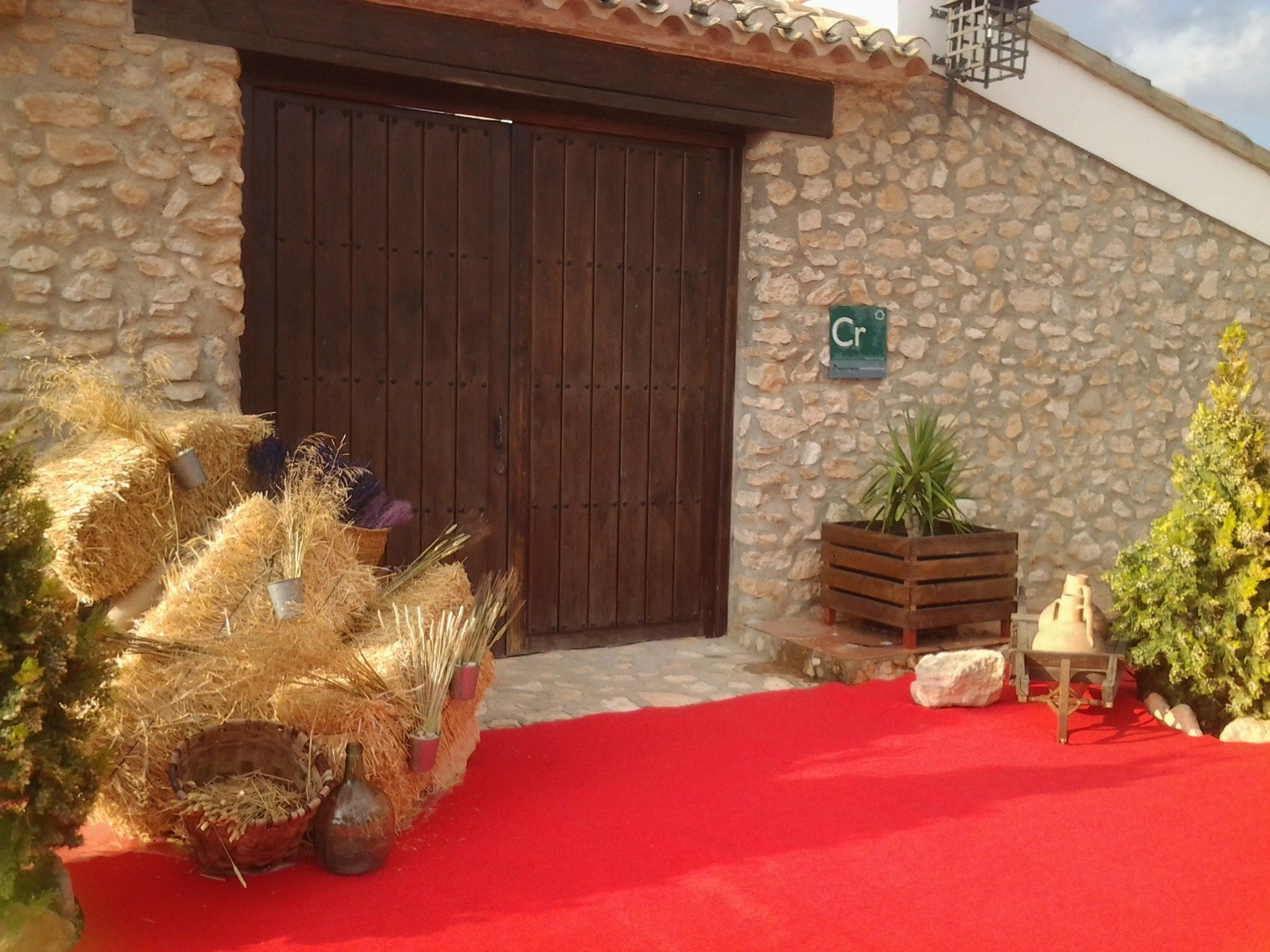 Un bâtiment rustique en pierre, doté d’une porte en bois et d’un tapis rouge menant à l’entrée.
